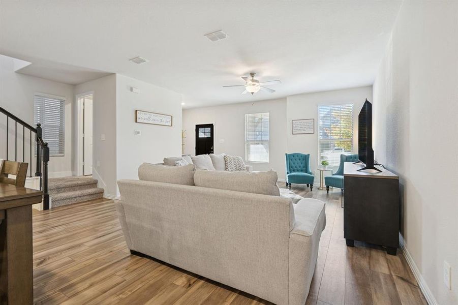 Living area with light wood-type flooring, stairs, and a ceiling fan