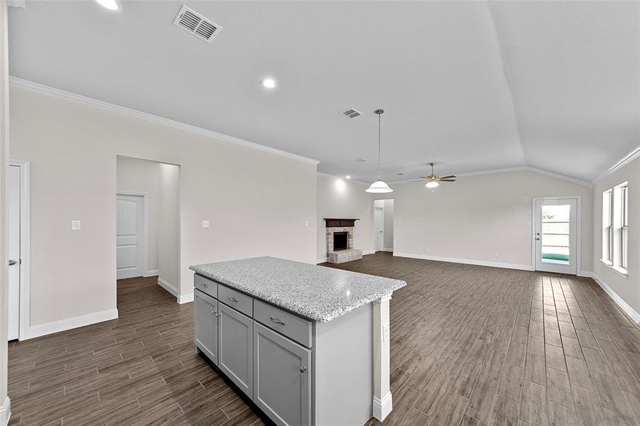 Kitchen with ceiling fan, vaulted ceiling, dark wood-type flooring, a fireplace, and gray cabinets