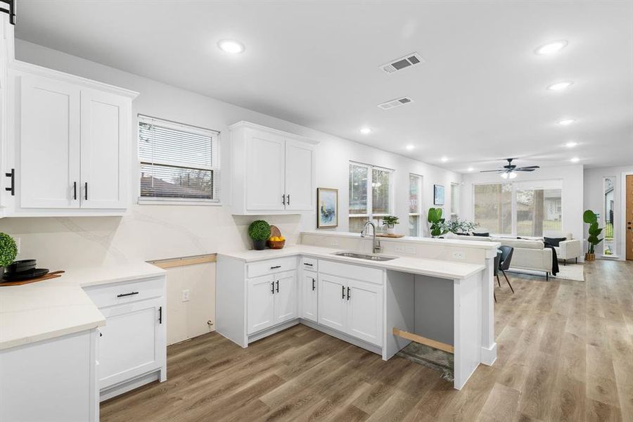 Kitchen featuring white cabinetry, sink, ceiling fan, kitchen peninsula, and light wood-type flooring