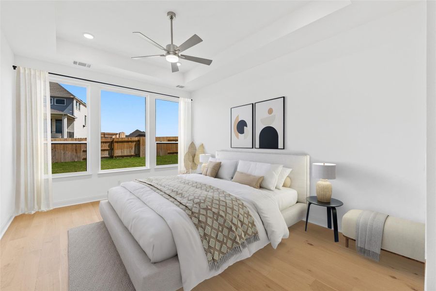 *Virtually Staged* Primary Bedroom featuring light wood-style floors, a raised ceiling, and a ceiling fan