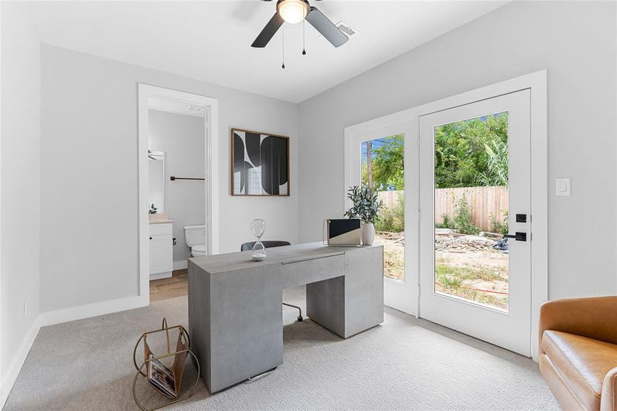 This light-filled secondary bedroom, which doubles as an office, seamlessly connects to the private backyard through expansive double glass doors, enhancing its utility.