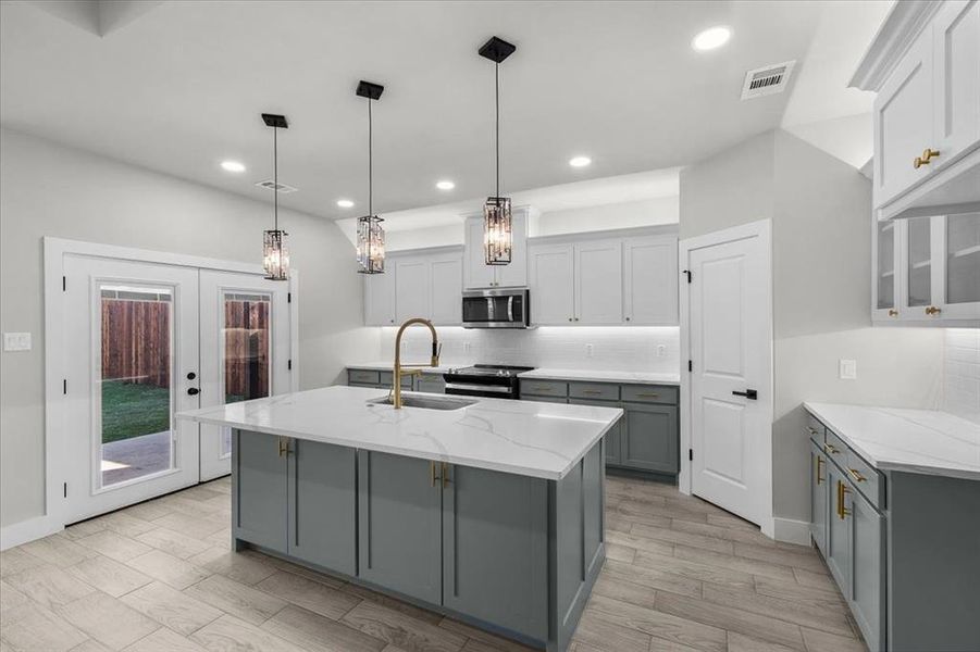 Kitchen featuring gray cabinetry, a sink, visible vents, appliances with stainless steel finishes, and tasteful backsplash