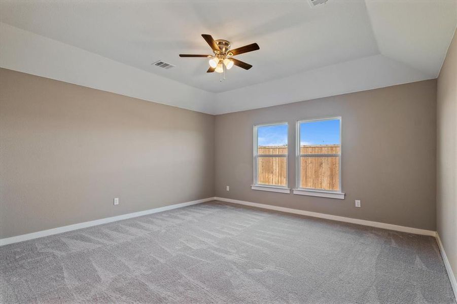 Carpeted bedroom featuring ceiling fan and vaulted ceiling