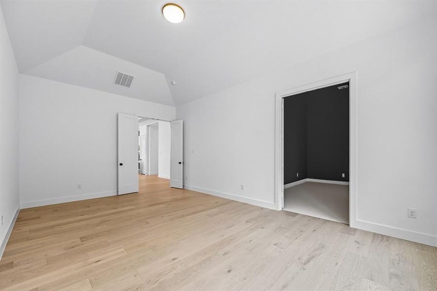 Unfurnished bedroom featuring light wood-type flooring and vaulted ceiling Unfurnished bedroom featuring light wood-type flooring and vaulted ceiling