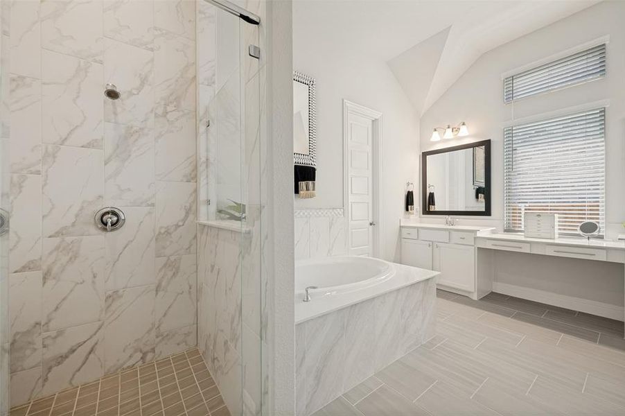Experience luxury every day in this stunning primary bathroom featuring a frameless glass walk-in shower with floor-to-ceiling marble-look tile, a relaxing garden tub, and soaring ceilings that create a bright, open feel. The extended vanity offers abundant storage and a dedicated makeup area beneath oversized windows that fill the space with natural light. Thoughtfully designed with elegant finishes and a timeless color palette, this spa-like retreat provides the perfect place to begin and end your day. Experience luxury every day in this stunning primary bathroom featuring a frameless glass walk-in shower with floor-to-ceiling marble-look tile, a relaxing garden tub, and soaring ceilings that create a bright, open feel. The extended vanity offers abundant storage and a dedicated makeup area beneath oversized windows that fill the space with natural light. Thoughtfully designed with elegant finishes and a timeless color palette, this spa-like retreat provides the perfect place to begin and end your day.