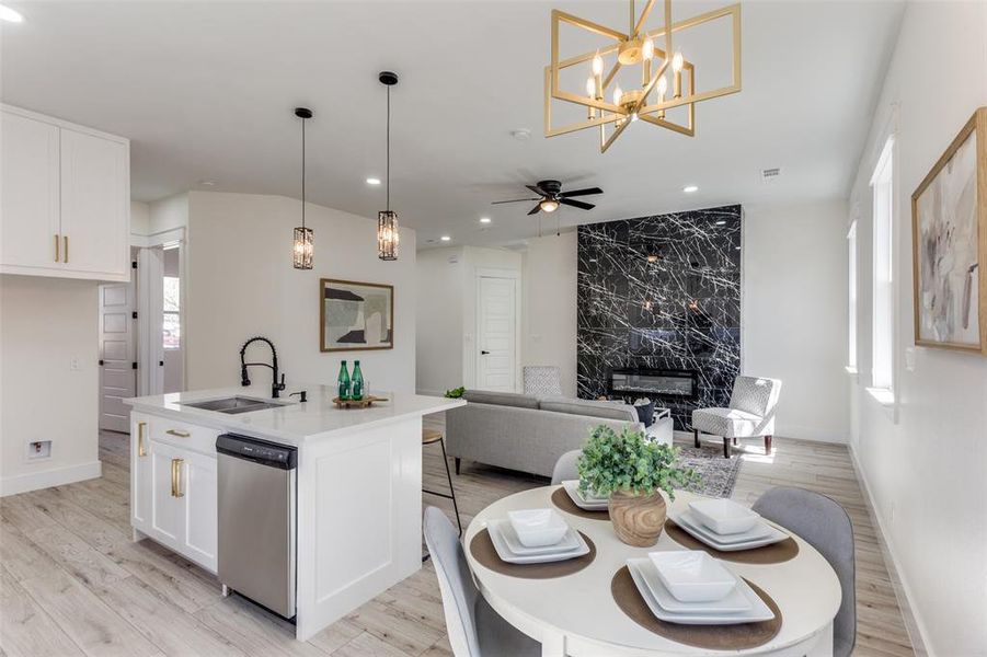 Kitchen with a sink, dishwasher, light wood-style flooring, and white cabinets