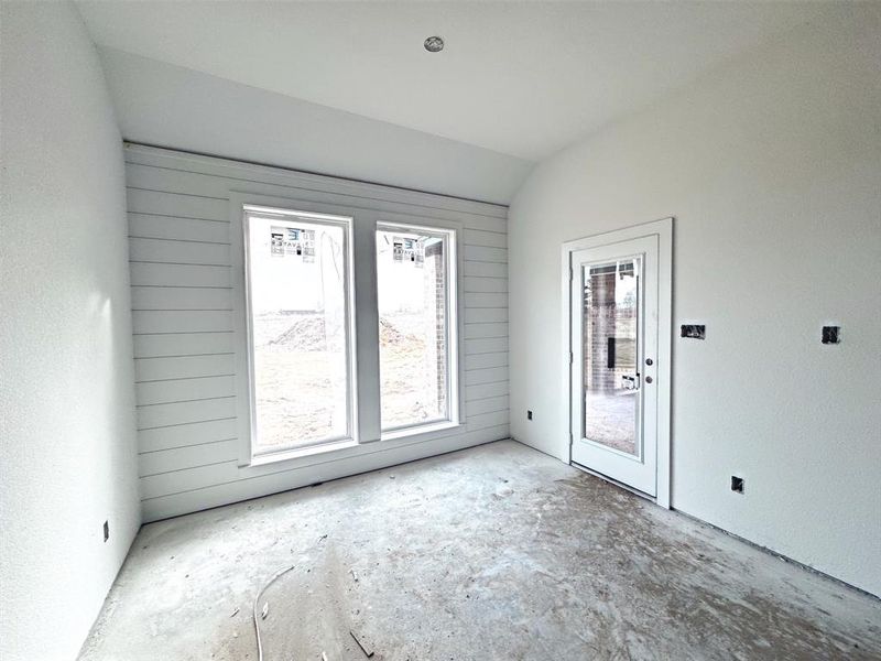 Empty room with lofted ceiling and wooden walls