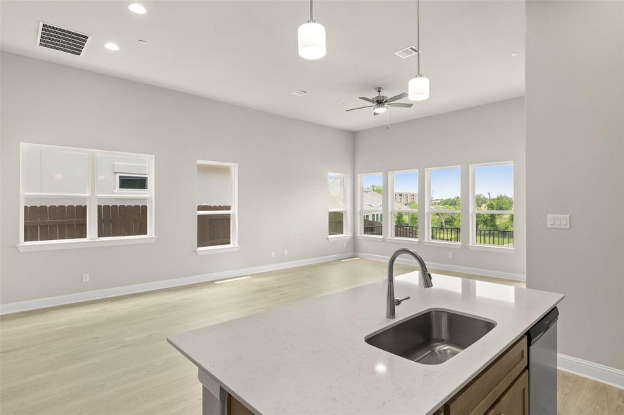 Kitchen featuring a sink, open floor plan, stainless steel dishwasher, pendant lighting, and ceiling fan