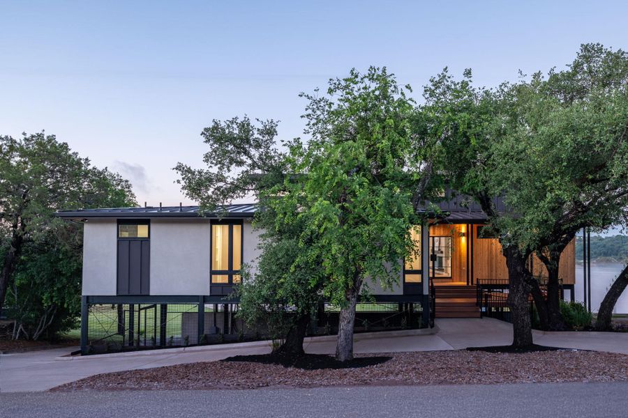 Modern architectural design featuring a split-level facade with stucco and wood siding, elevated on black pilings Modern architectural design featuring a split-level facade with stucco and wood siding, elevated on black pilings