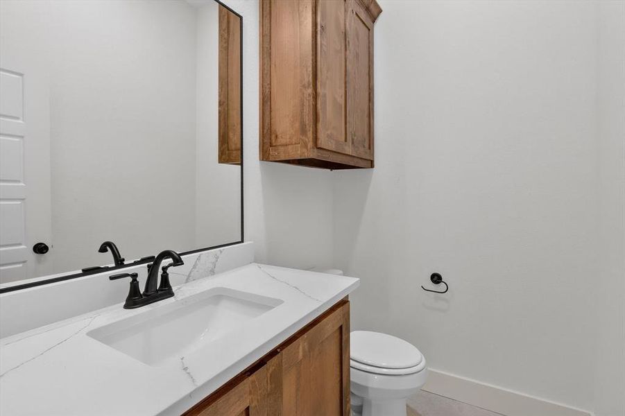 White vanity with an integrated rectangular sink, stone-finish countertop, matte black faucet, and coordinating hardware White vanity with an integrated rectangular sink, stone-finish countertop, matte black faucet, and coordinating hardware