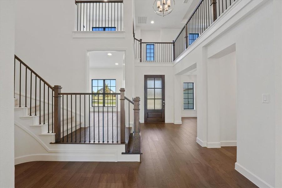 Entrance foyer with dark wood-style flooring, a towering ceiling, recessed lighting, stairway, and a chandelier