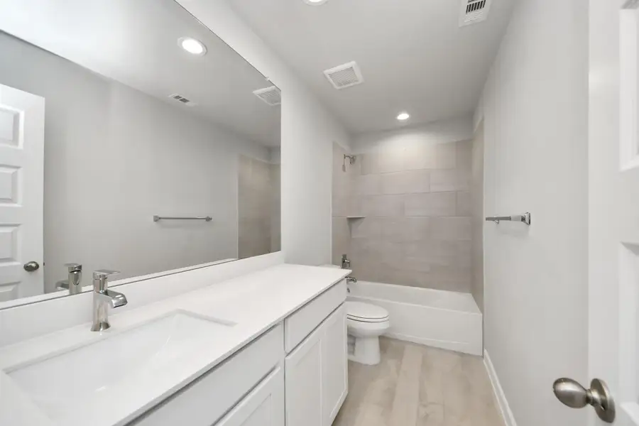 Secondary bath features tile flooring, bath/shower combo with tile surround, light stained wood cabinets, beautiful light countertop. Sample photo of completed home with similar floor plan. Actual colors and selections may vary. Secondary bath features tile flooring, bath/shower combo with tile surround, light stained wood cabinets, beautiful light countertop. Sample photo of completed home with similar floor plan. Actual colors and selections may vary.
