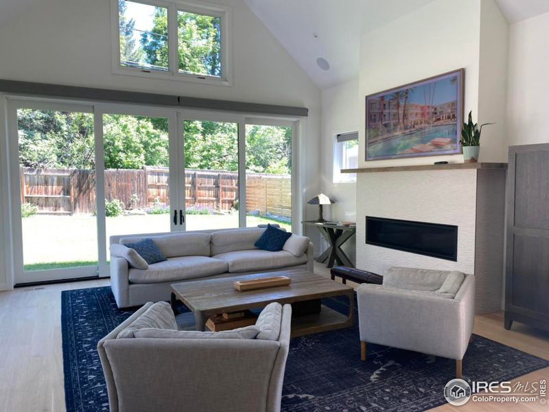 Living area with gas fireplace, peaked ceilings and motorized window shades