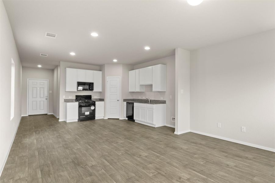 Kitchen with black appliances, recessed lighting, light wood-style flooring, and white cabinets