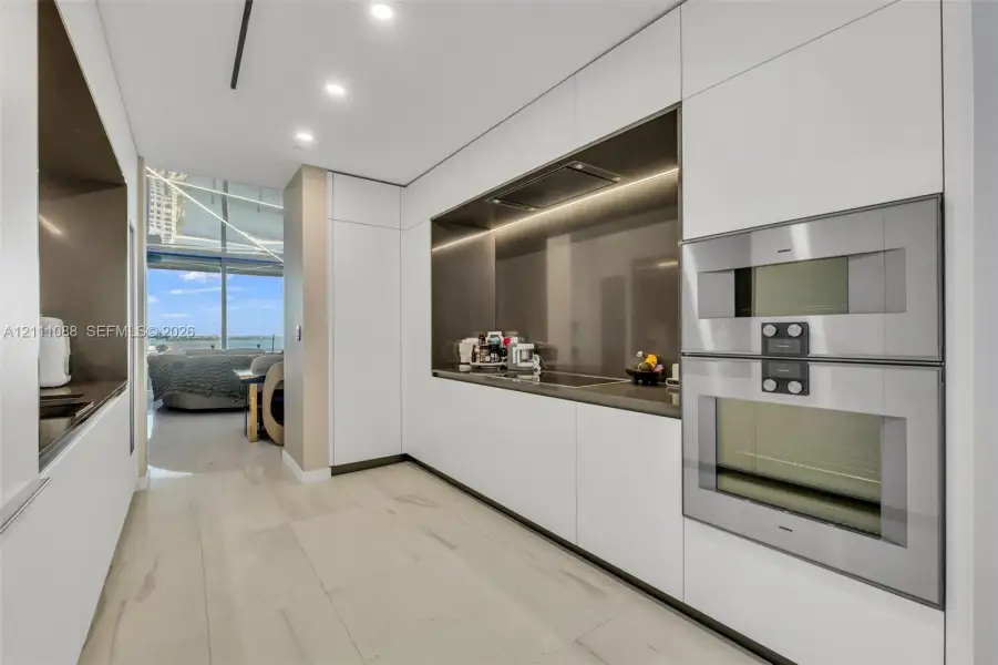 Sleek kitchen featuring floor-to-ceiling cabinetry, integrated stainless steel double wall ovens, recessed lighting, and solid-surface countertops Sleek kitchen featuring floor-to-ceiling cabinetry, integrated stainless steel double wall ovens, recessed lighting, and solid-surface countertops