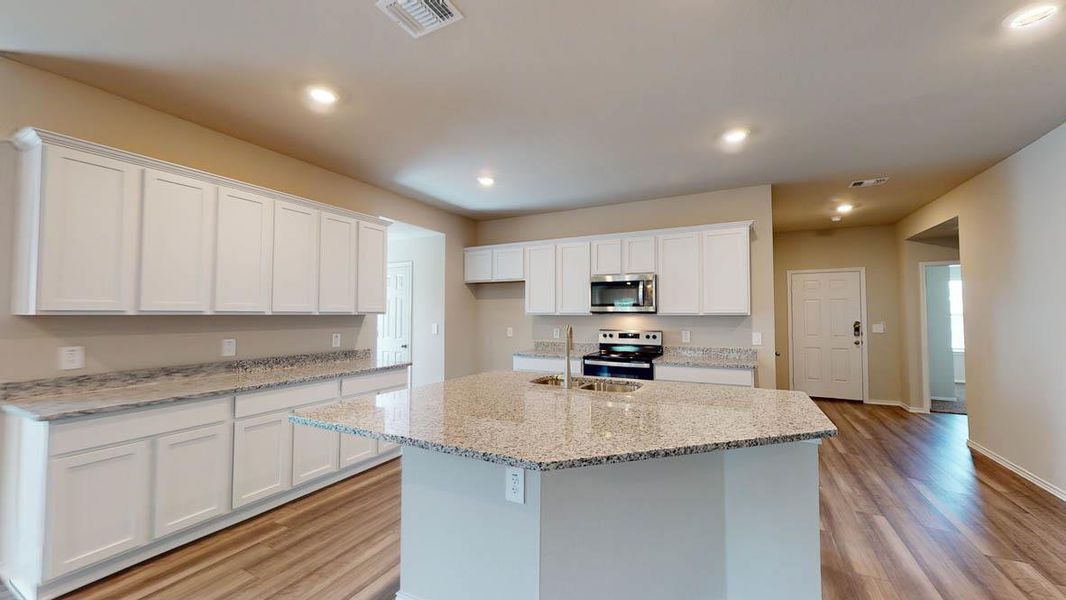 Kitchen featuring white cabinetry, light stone counters, stainless steel appliances, a kitchen island with sink, and light wood-type flooring