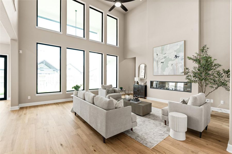 Stunning living room with soaring ceilings, expansive windows for natural light, and a modern fireplace accentuating the open space. *Virtually Staged*
