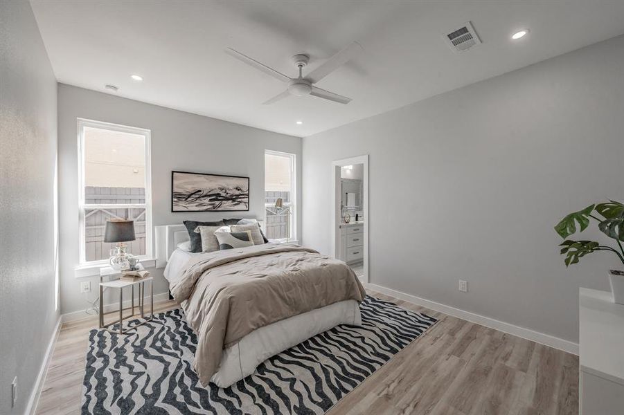 Bedroom with multiple windows, ceiling fan, connected bathroom, and light wood-type flooring