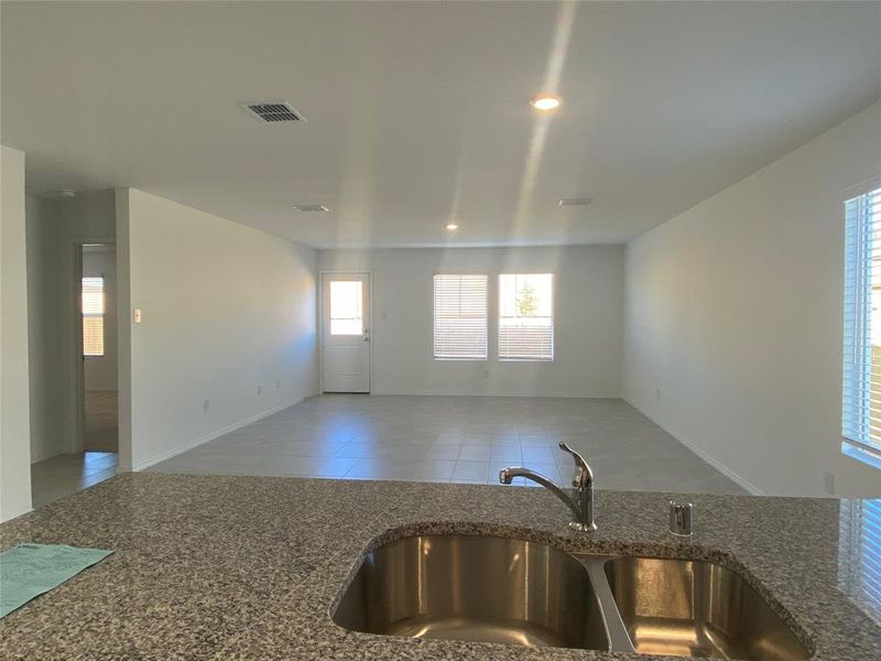 Kitchen with visible vents, open floor plan, tile patterned flooring, a sink, and dark stone counters