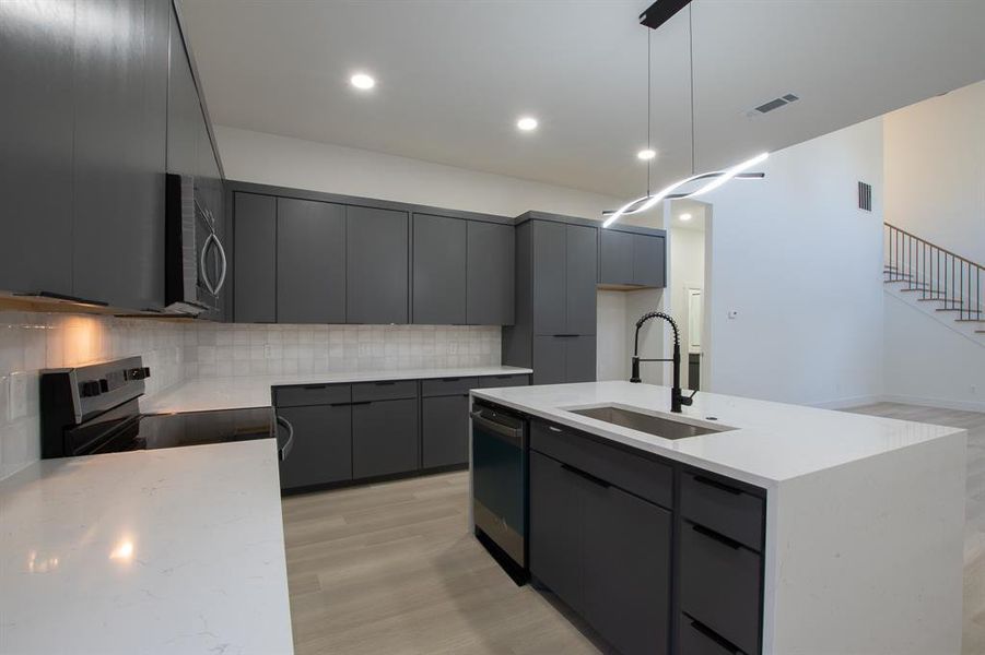 Kitchen with a kitchen island with sink, gray cabinets, appliances with stainless steel finishes, and sink