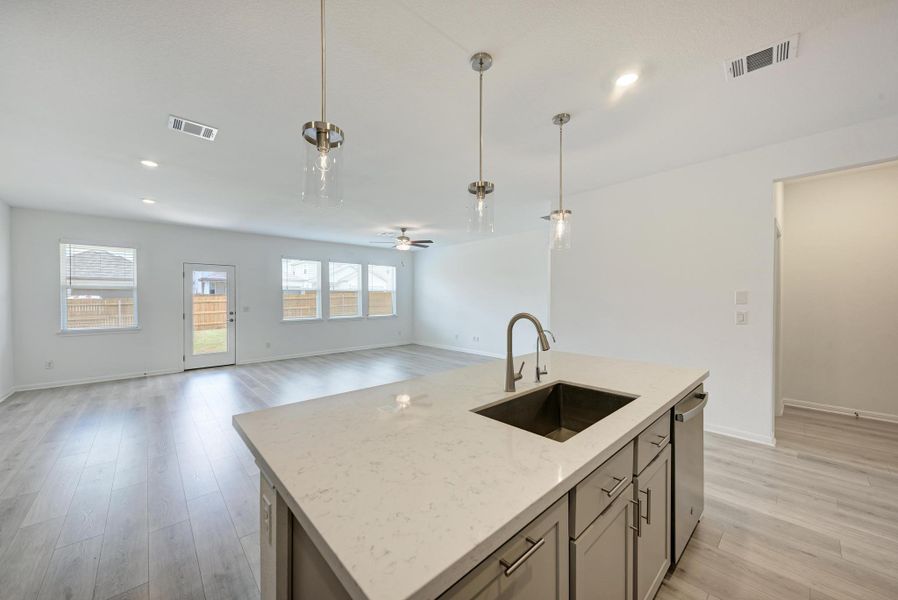 A well-appointed kitchen island with sleek counters anchors this naturally illuminated, open-concept living space.