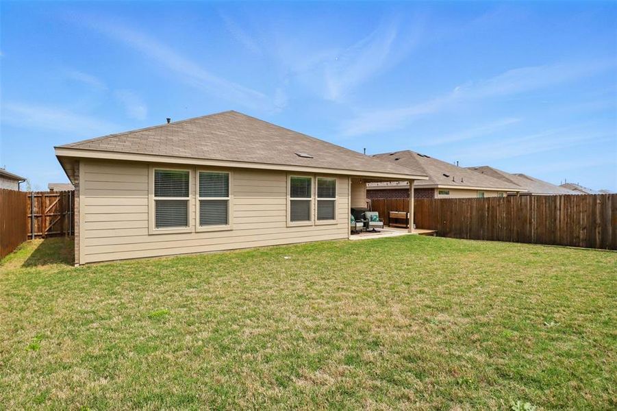 Back of property with a fenced backyard, a lawn, and a patio