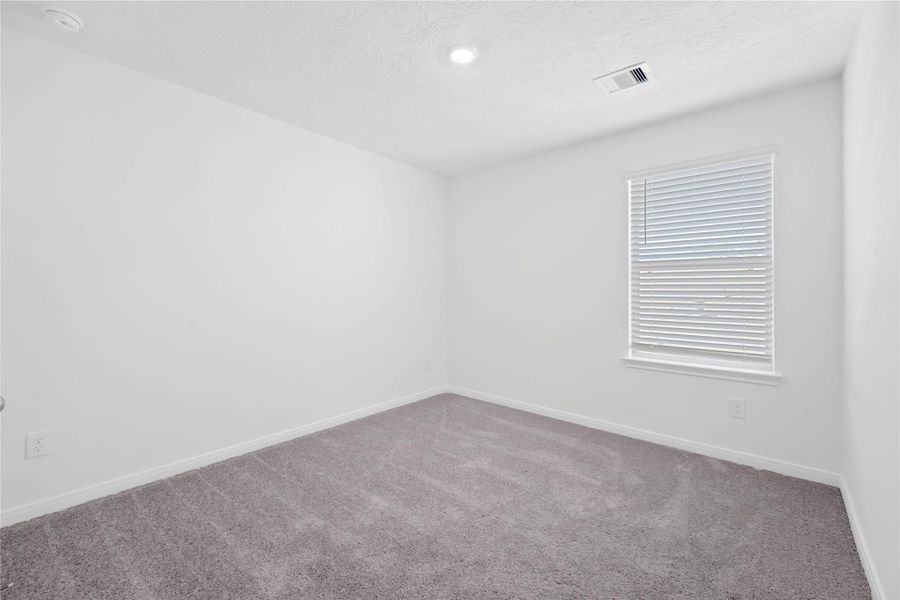 Secondary bedroom features plush carpet, neutral paint, lighting, large windows with privacy blinds, and ample sized closet space.