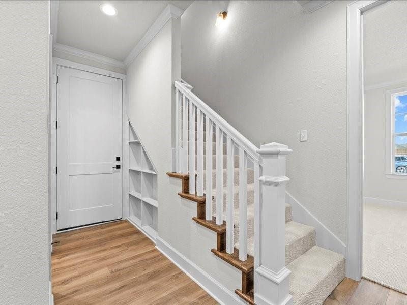 Stairway with ornamental molding and wood finished floors