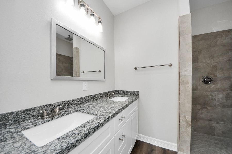 The primary bathroom combines elegance and practicality, showcasing a stunning mud-set shower with a rainfall showerhead, a spacious granite vanity with dual sinks, and plenty of cabinet space to keep everything organized and within reach - (representation photo).