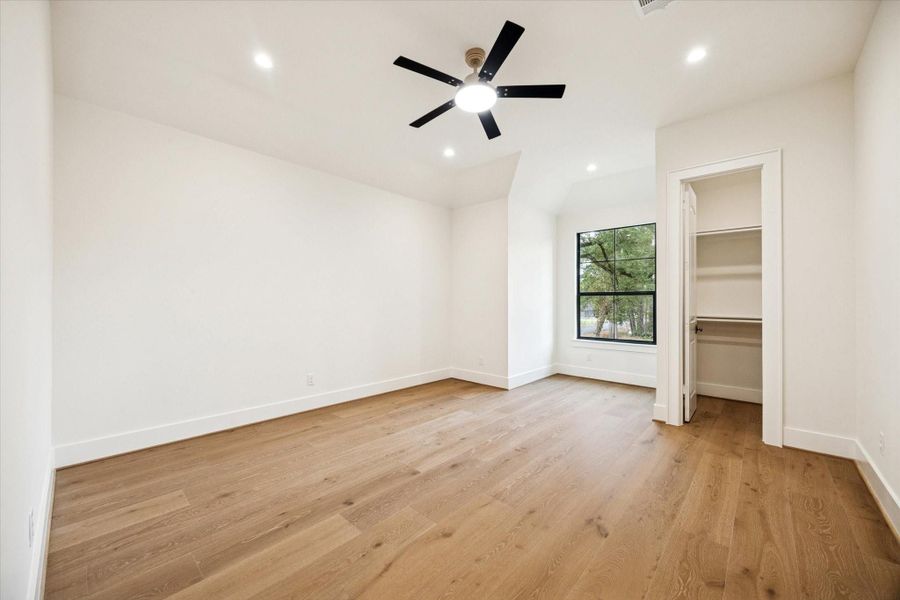 Third bedroom with white oak wood floors, recessed lighting, ceiling fan, and walk-in closet.