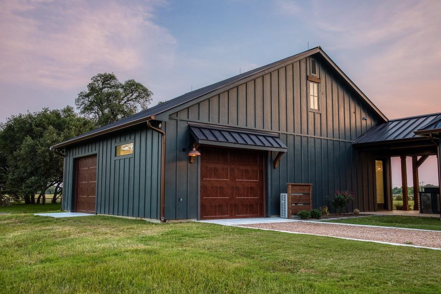 View of front of property featuring board and batten siding, a garage, and a yard View of front of property featuring board and batten siding, a garage, and a yard