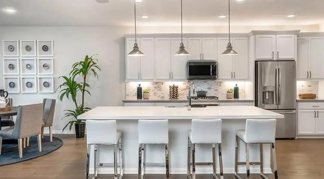 Kitchen featuring appliances with stainless steel finishes, a kitchen breakfast bar, dark wood-style floors, decorative backsplash, and recessed lighting
