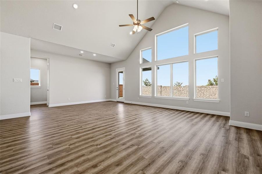 Unfurnished living room with a ceiling fan, a high ceiling, dark wood-style floors, and recessed lighting Unfurnished living room with a ceiling fan, a high ceiling, dark wood-style floors, and recessed lighting