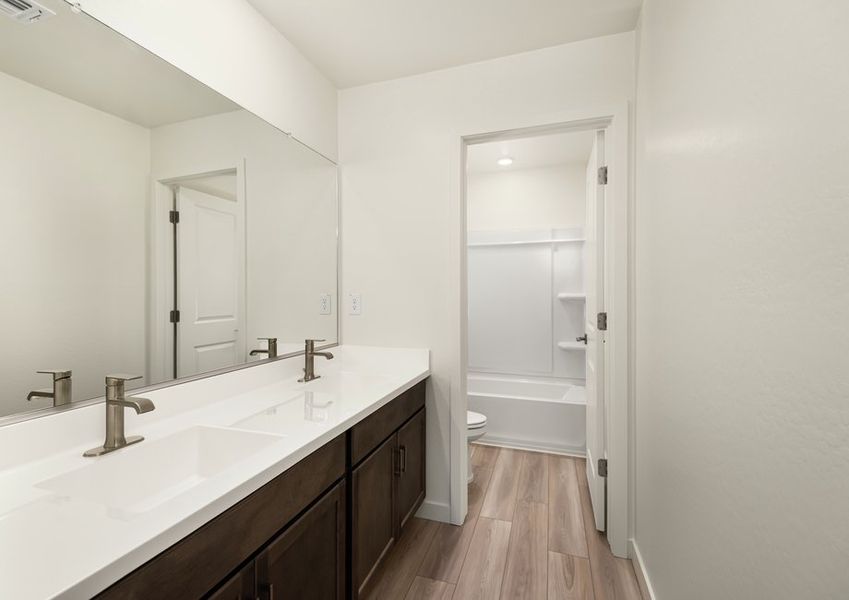 The master bathroom features dual-vanity sinks and a glass-enclosed  shower.