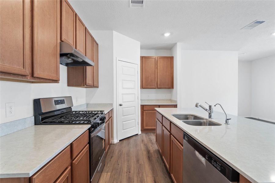 A true chef’s dream, this expansive kitchen boasts high ceilings, rich stained wood cabinets, Silestone countertops in Lusso, stainless steel appliances, recessed lighting, extended counter space, an island with added breakfast bar, and a walk-in pantry—all with a clear view of the spacious family room.