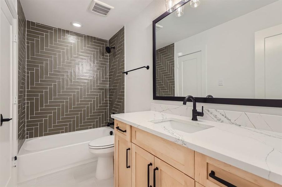 Full bathroom featuring tiled shower / bath combo, vanity, and toilet