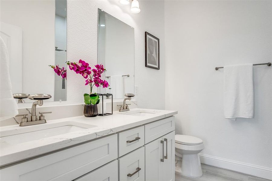 Full bathroom featuring double vanity and light wood-style flooring Full bathroom featuring double vanity and light wood-style flooring