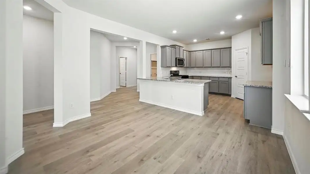 Kitchen featuring gray cabinetry, decorative backsplash, light stone counters, recessed lighting, and black range oven