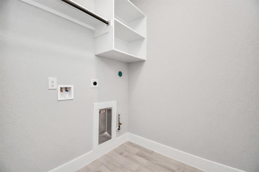 Stylish laundry room where practicality meets a contemporary aesthetic. Built-in shelving, and the dark finishes lend a sophisticated touch, creating a space that is both functional and visually appealing. Both electric and gas connections available.