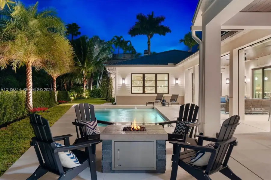 Covered patio featuring a concrete deck, built-in fire pit with stone-finish base, rectangular swimming pool, and landscape lighting Covered patio featuring a concrete deck, built-in fire pit with stone-finish base, rectangular swimming pool, and landscape lighting