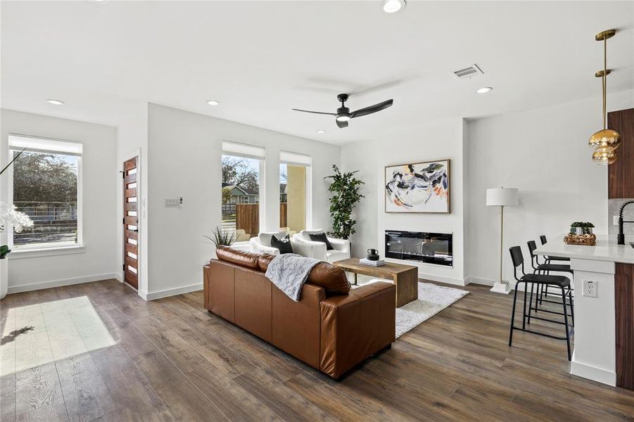 Living room featuring plenty of natural light, ceiling fan, and dark wood-type flooring