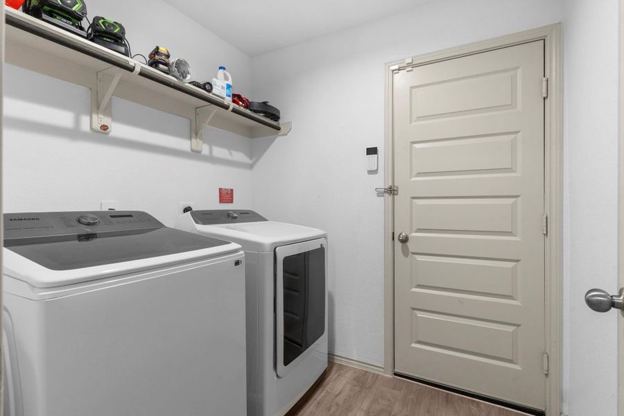 Spacious utility room with built-in shelving for extra storage, full-size washer/dryer connections, and convenient access to the garage — keeping household tasks organized and efficient. Spacious utility room with built-in shelving for extra storage, full-size washer/dryer connections, and convenient access to the garage — keeping household tasks organized and efficient.