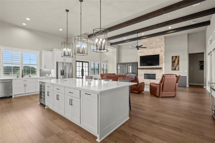 An open concept living area features a grand kitchen island, exposed ceiling beams, and a commanding stone fireplace. An open concept living area features a grand kitchen island, exposed ceiling beams, and a commanding stone fireplace.