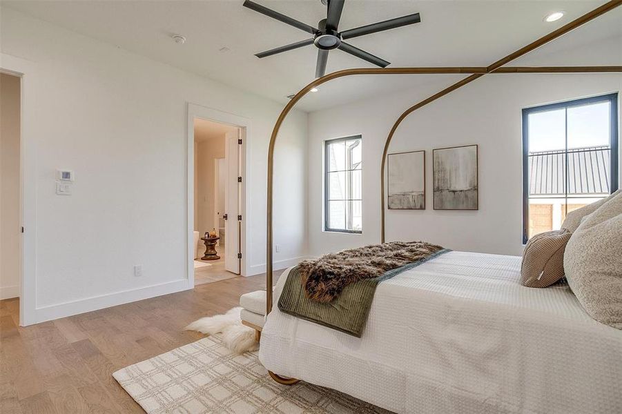 Bedroom featuring ensuite bathroom, light wood-type flooring, and ceiling fan