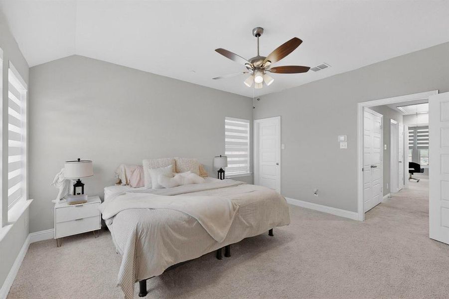 Bedroom featuring vaulted ceilings, light-colored carpeting, and a ceiling fan with integrated lighting