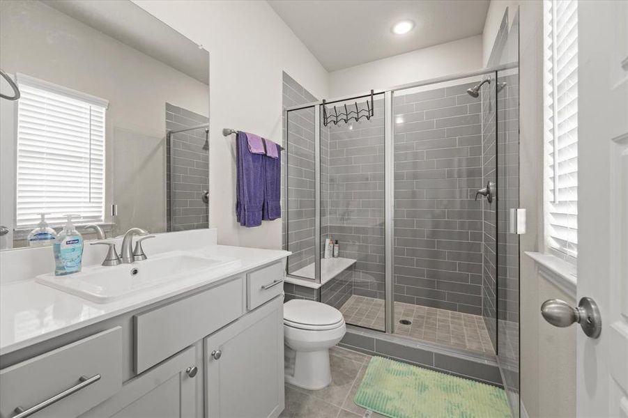 Bathroom featuring vanity, tile patterned flooring, toilet, and a shower with shower door