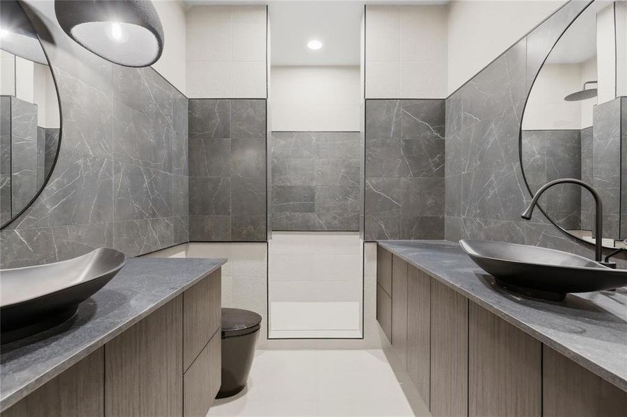 Dual floating vanities featuring wood-finish cabinetry, dark stone countertops, and vessel sinks with matte black fixtures