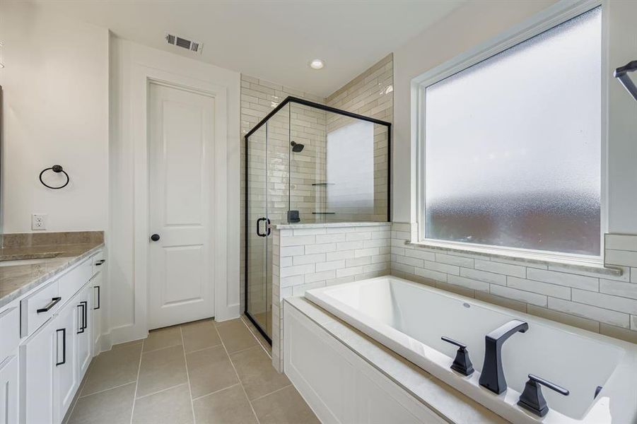 Full bath featuring a stall shower, vanity, a bath, light tile patterned flooring, and recessed lighting Full bath featuring a stall shower, vanity, a bath, light tile patterned flooring, and recessed lighting