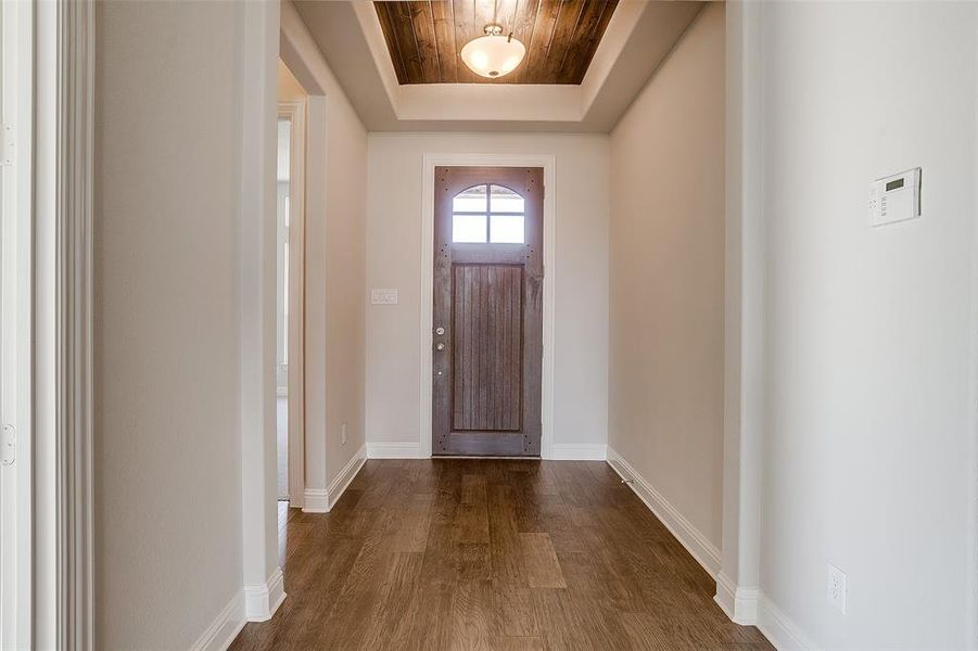 Foyer with wood ceiling, dark wood-type flooring, and a tray ceiling