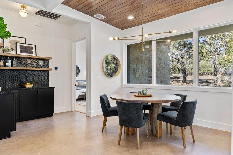 Dining area with finished concrete floors, wood ceiling, a chandelier, bar with sink, and recessed lighting